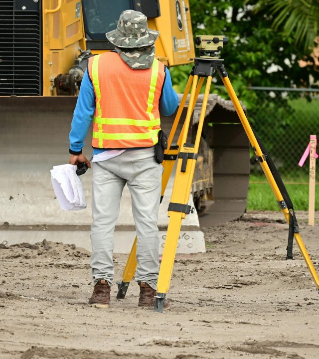 A surveyor with equipment conducts measurements on a construction site.